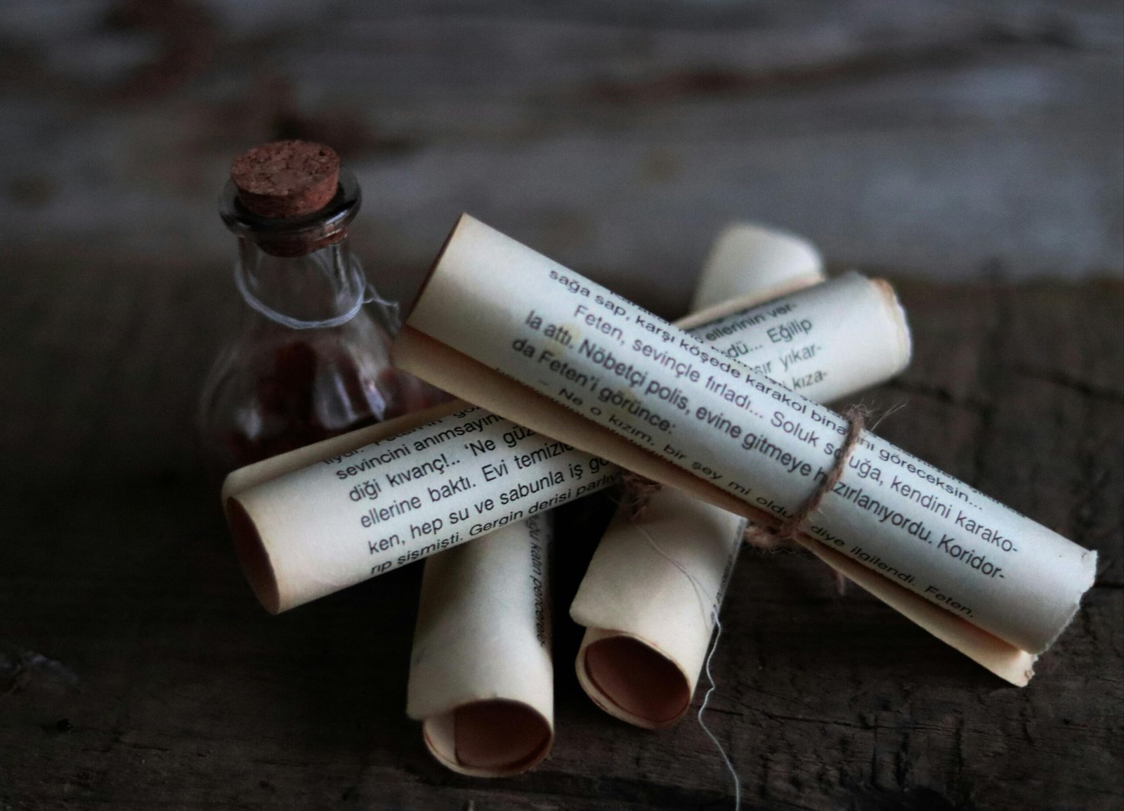 Artistic arrangement of rolled papers and a corked bottle conveying a vintage, mysterious feel.
